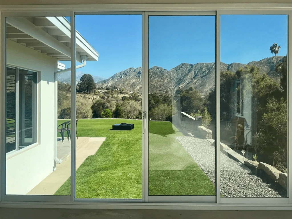 Streak-free sliding glass doors framing a green lawn and mountain view