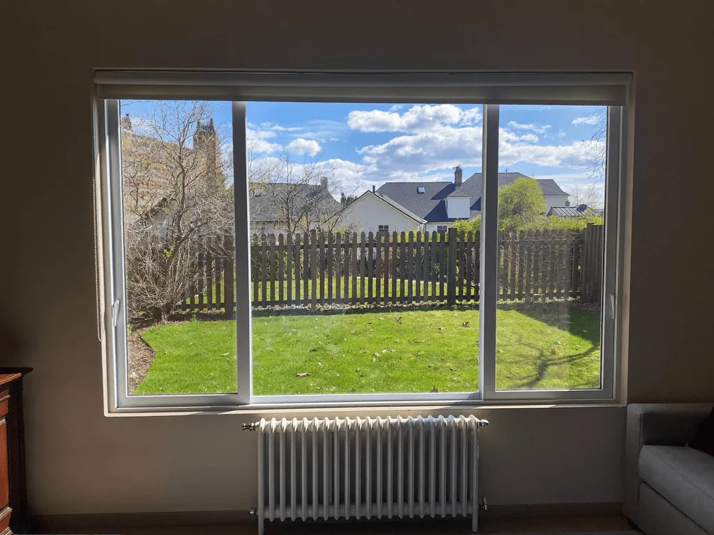 Spotless interior picture window framing a sunny backyard and bright blue sky