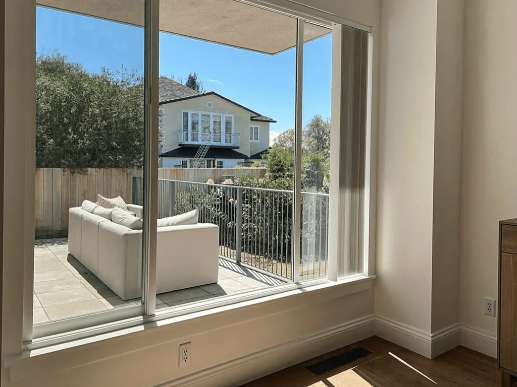 Spotless picture window framing a patio and neighboring house